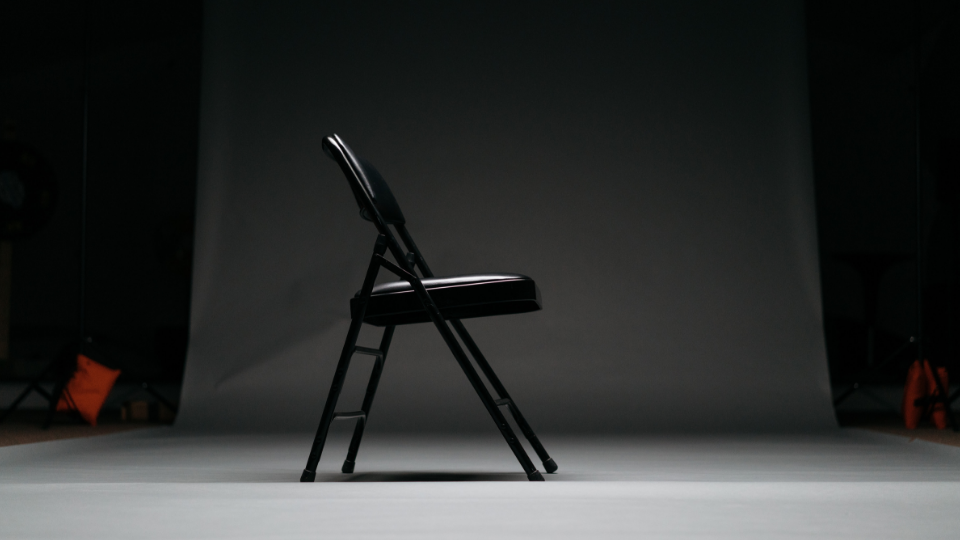black folding chair sitting on white backdrop