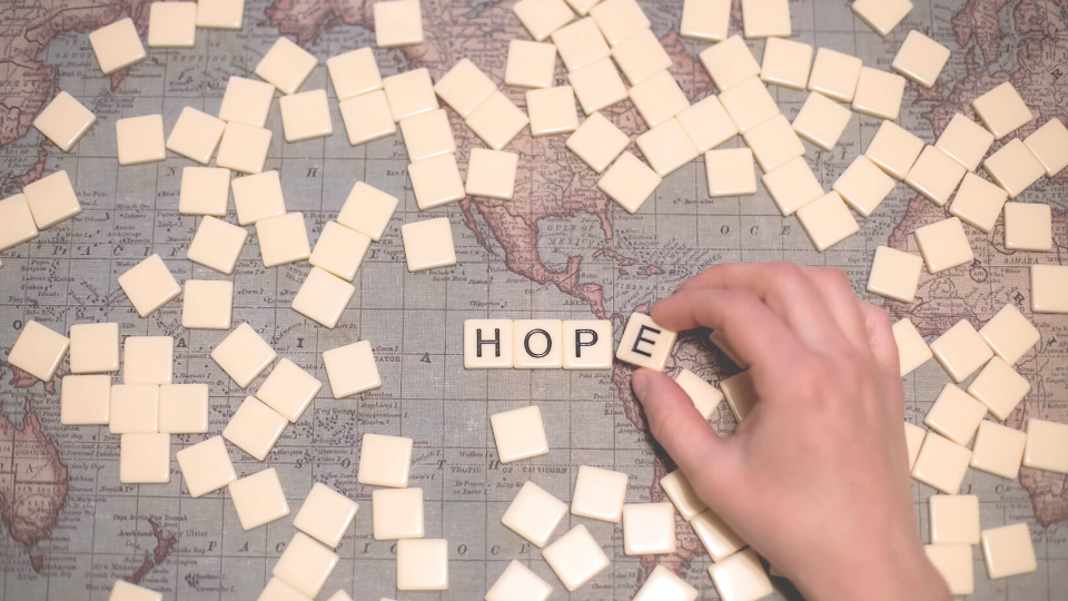 World map with word "HOPE" spelled out on top in scrabble letters