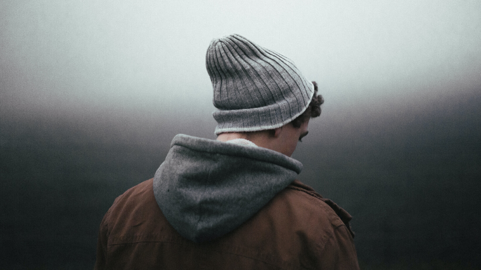 boy with grey beanie and grey sweatshirt looking down at the ground