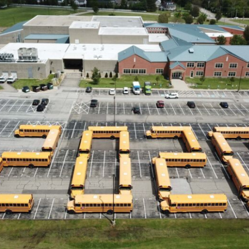 yellow school buses organized in a school parking lot to write 2020
