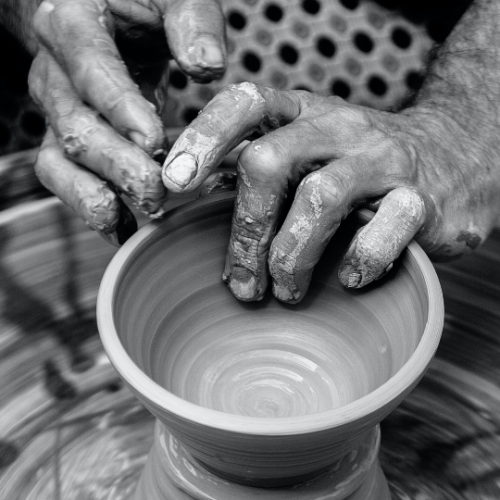 black and white photo of someone's hands molding a clay bowl