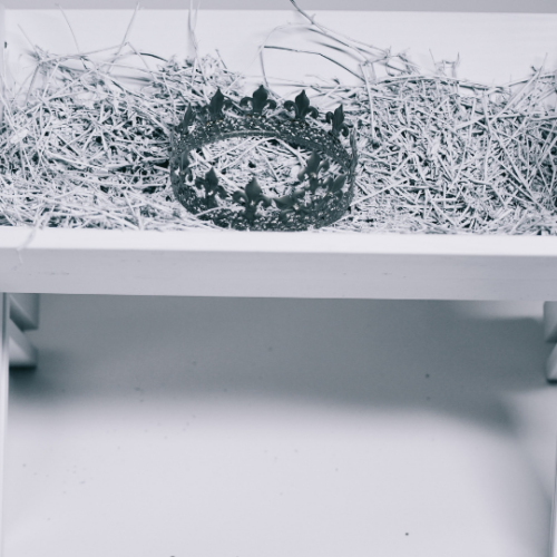 black and white picture of a wooden manger with straw in it and a crown sitting on top