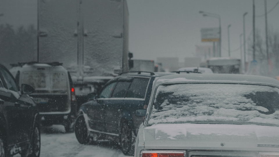 cars and trucks in traffic on a highway covered with snow