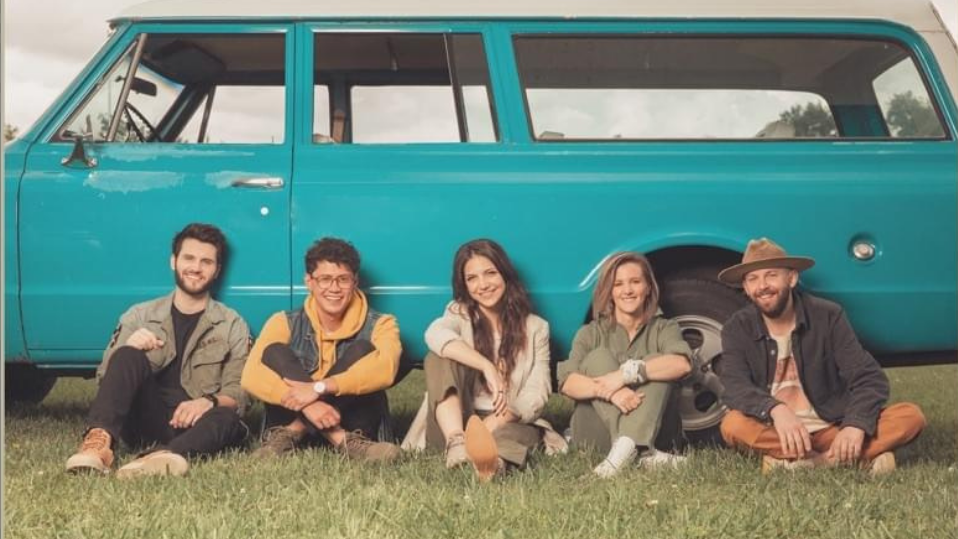 the five members of I Am They sitting against a parked turquoise vintage volkswagen van