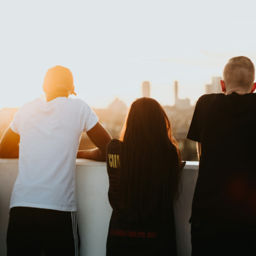 Four people standing next to one another staring at the skyline of a city